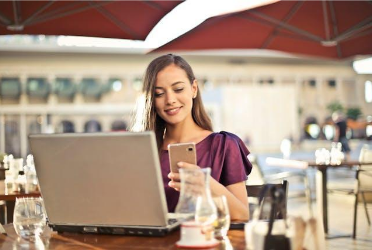 A woman sitting outside while looking at her phone.